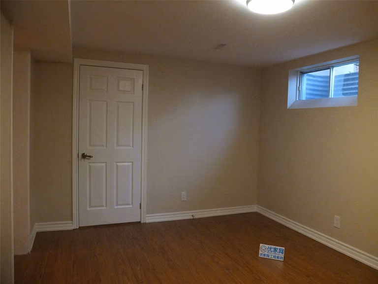 This Markham basement renovation project features newly finished walls, fresh interior painting, and durable laminate flooring installation. The clean wall finish, neutral paint tones, and wood-style flooring create a bright, comfortable living space suitable for a family recreation room or additional living area. Careful detailing around the baseboards and wall edges ensures a smooth and polished appearance throughout the basement interior.