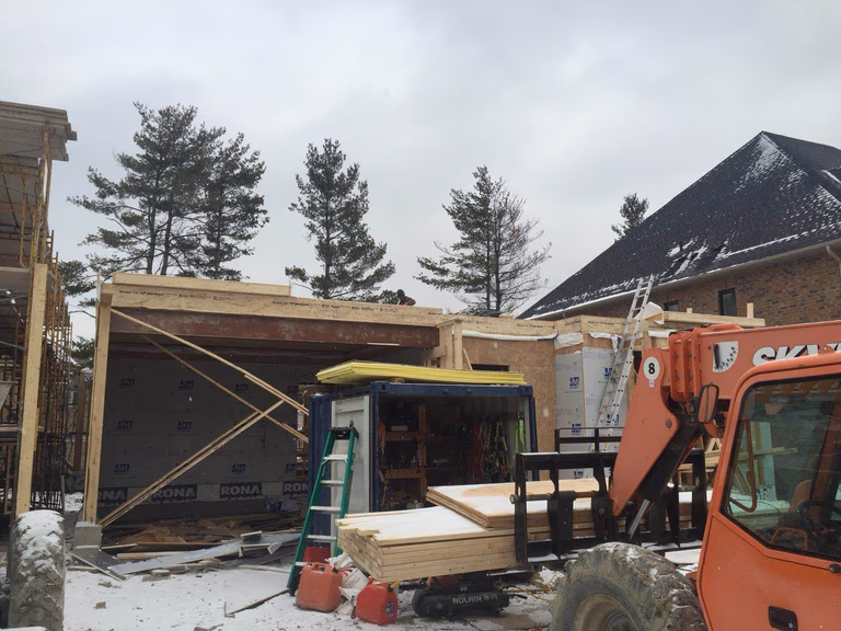 Active construction site for a Toronto design build custom build project, showing structural framing work, construction equipment, and building materials prepared for installation. This stage is part of a whole house renovation Toronto and custom home construction process, where contractors coordinate structural assembly, material delivery, and site preparation to ensure the project progresses efficiently and meets modern building standards.