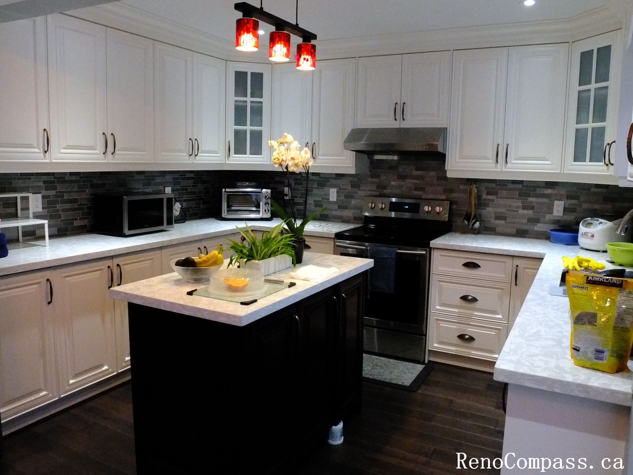 This Richmond Hill kitchen renovation showcases a modern white cabinet design with a central island, quartz countertops, and stainless steel appliances. The space is enhanced by stylish pendant lighting and a sleek backsplash, creating a clean and functional cooking environment. Completed by a Toronto renovation company, this project highlights contemporary kitchen design with practical layout and elegant finishes.