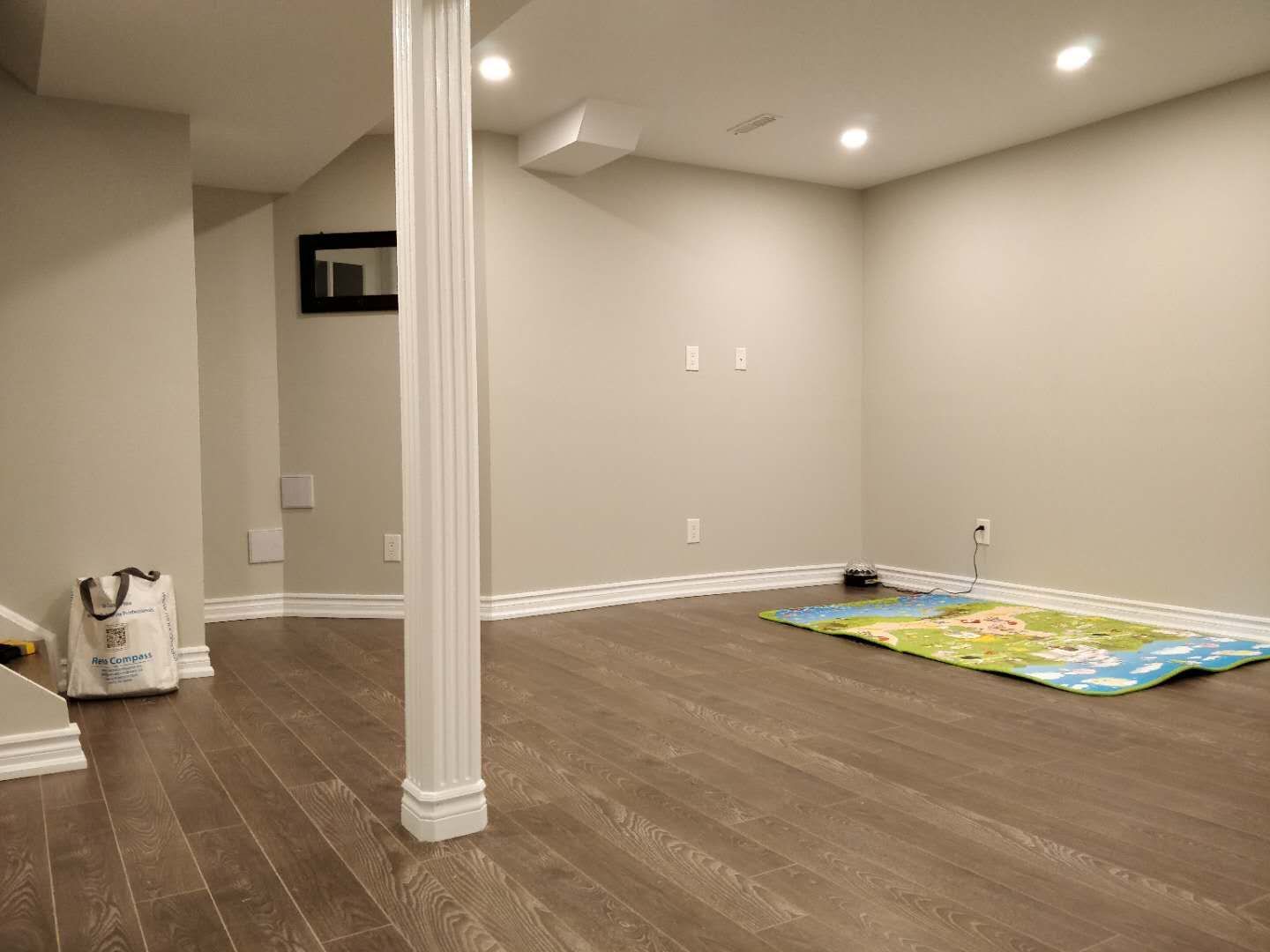 This Scarborough basement renovation features a spacious finished area with modern pot lighting, fresh painted walls, and high-quality hardwood flooring. A structural support column is seamlessly integrated into the layout while maintaining an open and functional design. The renovation transforms the basement into a bright and practical living space, completed by a professional Toronto renovation company.