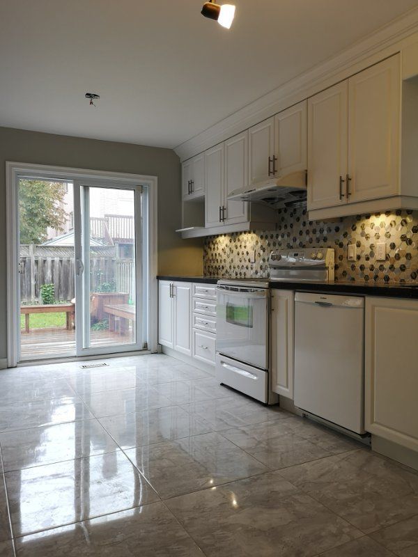 This image showcases a bright and refined hallway renovation in Mississauga, featuring polished tile flooring, soft neutral wall colors, and a custom curved staircase with black iron railings. The redesign improves visual flow from the entryway while enhancing natural light and spatial depth. Completed by an experienced Toronto renovation company, this interior renovation focuses on craftsmanship, elegant circulation, and long-term residential value.