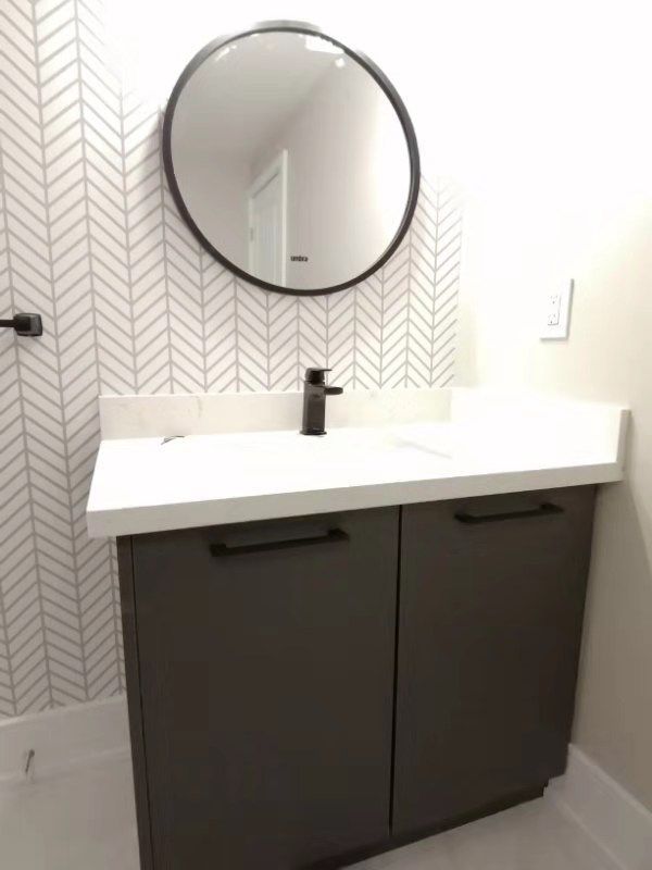 This Richmond Hill bathroom renovation features a modern vanity with custom dark cabinetry, white quartz countertop, matte black faucet, and a stylish round mirror. The herringbone accent wall adds texture and elegance, creating a clean and contemporary powder room design. Completed by professional Toronto renovation company Reno Compass Inc., this project highlights quality finishes, smart storage, and timeless modern bathroom aesthetics perfect for today’s homes.