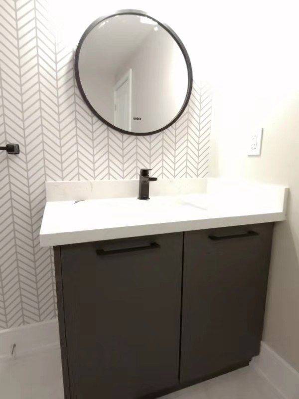 This Richmond Hill bathroom renovation features a modern vanity with custom dark cabinetry, white quartz countertop, matte black faucet, and a stylish round mirror. The herringbone accent wall adds texture and elegance, creating a clean and contemporary powder room design. Completed by professional Toronto renovation company Reno Compass Inc., this project highlights quality finishes, smart storage, and timeless modern bathroom aesthetics perfect for today’s homes.