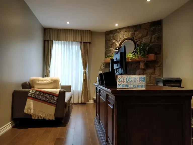 This finished living area is part of a North York interior renovation, featuring a natural stone accent wall paired with custom wood cabinetry and warm hardwood flooring. Recessed ceiling lighting and full-height window treatments enhance natural light while maintaining a calm and comfortable atmosphere. The layout is designed for everyday living, combining visual character with functional furniture placement. Completed by a Toronto renovation company, this interior renovation highlights material contrast, balanced lighting, and cohesive design throughout the space.