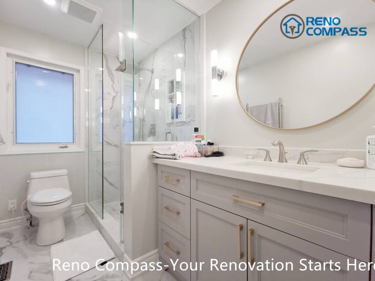 This Mississauga bathroom renovation features a custom vanity with soft grey cabinetry, brushed gold hardware, and a clean quartz countertop. A round framed mirror paired with vertical wall sconces provides balanced lighting for daily use while enhancing the overall elegance of the space. Thoughtful storage design and refined finishes reflect the attention to detail and craftsmanship expected from a professional Toronto renovation company.