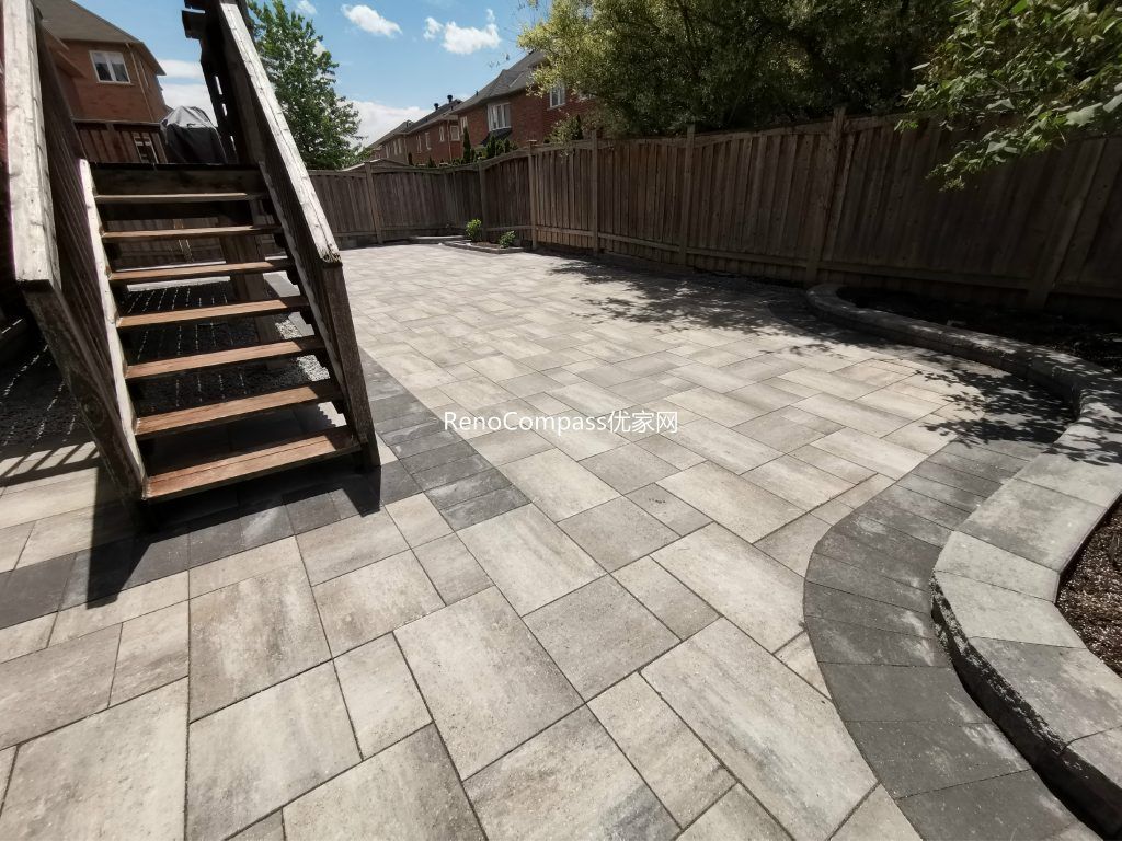 Backyard interlocking patio project in Richmond Hill designed around a wooden deck. Featuring clean, neutral-toned stones arranged for durability and aesthetic appeal — a perfect balance of function and style by Reno Compass.