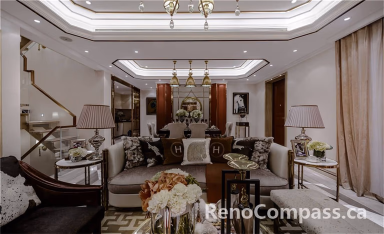 This Toronto interior renovation highlights a sophisticated living room featuring layered tray ceiling detailing, custom lighting design, and a balanced open-concept layout connecting the lounge and dining space. Warm wood accents, marble flooring, and refined décor elements create a luxurious yet welcoming atmosphere. Completed by a trusted Toronto Renovation Company, this project reflects high-end craftsmanship, thoughtful spatial planning, and timeless interior elegance suitable for upscale residential living.