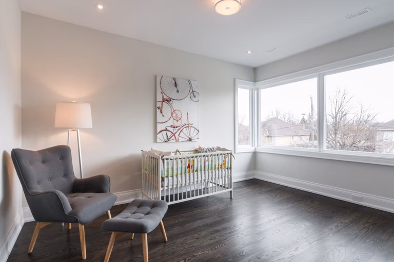 This bright and comfortable nursery room is part of a 4,500 sq ft luxury home renovation in Toronto. Designed with large corner windows and warm hardwood flooring, the space offers a calm and welcoming environment for modern family living. Clean wall finishes and thoughtful layout planning enhance both natural light and functionality. Completed by a professional Toronto Renovation Company, Reno Compass Inc., this project reflects quality craftsmanship and contemporary residential design tailored for growing families.