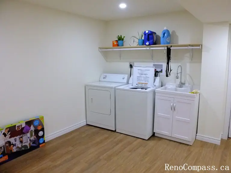 This Richmond Hill basement renovation features a clean and functional laundry room with upgraded washer and dryer, custom shelving, integrated utility sink, and durable flooring. The bright recessed lighting and smart layout maximize space efficiency while maintaining a modern aesthetic. Completed by a trusted Toronto Renovation Company, this basement transformation combines practicality with polished design.