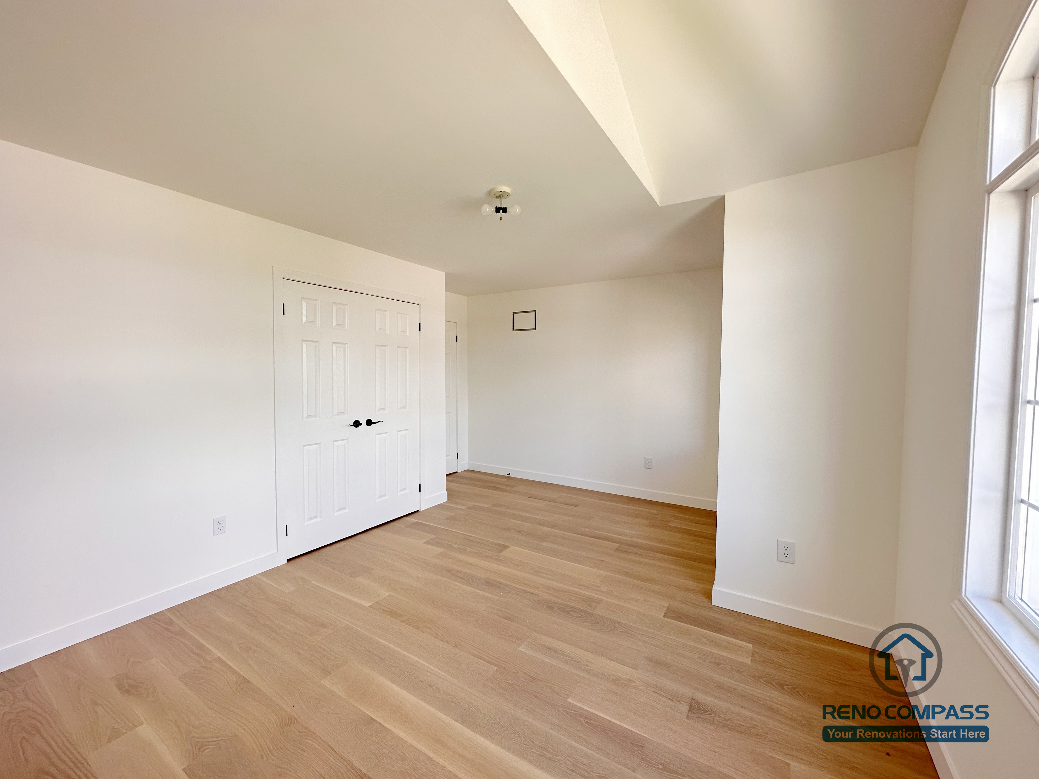 This image highlights a Markham bedroom flooring renovation featuring wide-plank hardwood floors, clean white walls, and a built-in double-door closet. The layout emphasizes practical storage, clear circulation, and a calm, uncluttered atmosphere suitable for everyday living. Natural light from the adjacent window enhances the warmth of the wood flooring and improves overall spatial comfort. Completed by a trusted Toronto renovation company, Reno Compass Inc., this project demonstrates precise flooring installation and thoughtful residential interior detailing.