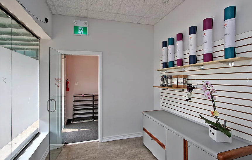 Interior renovation of a Richmond Hill yoga studio featuring a modern retail display wall, custom shelving for yoga mats and accessories, and a clean reception-side layout. The commercial renovation includes upgraded flooring, glass entrance door installation, fresh wall finishes, and improved lighting to create a bright and welcoming retail and studio entry space. Completed by a professional Toronto renovation company, this project enhances both functionality and customer experience for wellness and fitness businesses.