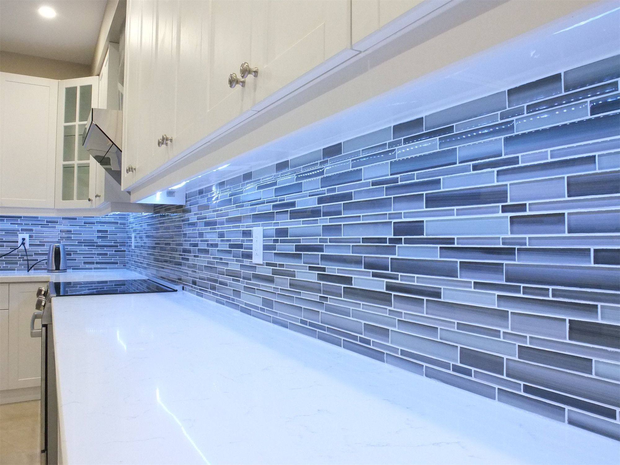 Detailed view of the quartz countertop and modern glass mosaic tile backsplash in this Vaughan kitchen renovation. The sleek tile pattern paired with LED under-cabinet lighting adds texture and depth to the space while maintaining a clean contemporary look. Completed by a professional Toronto renovation company, the design highlights both craftsmanship and modern kitchen finishes.