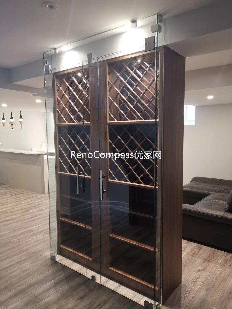 This Richmond Hill basement renovation features a custom glass wine cabinet with built-in wood shelving and integrated lighting, designed to enhance both storage and display. The elegant craftsmanship and functional layout complement the modern basement bar and entertainment space, completed by a trusted Toronto renovation company specializing in full house and basement renovations.