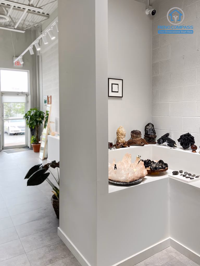 This image highlights a custom-built crystal display corner in a renovated crystal shop located in Markham. The design features clean white display niches, minimalist shelving, and focused lighting to enhance the visual impact of crystals and spiritual items. Neutral wall finishes and polished flooring create a calm, gallery-like retail atmosphere. As a Toronto renovation company, Reno Compass specializes in boutique retail renovations that balance aesthetics, functionality, and customer flow.