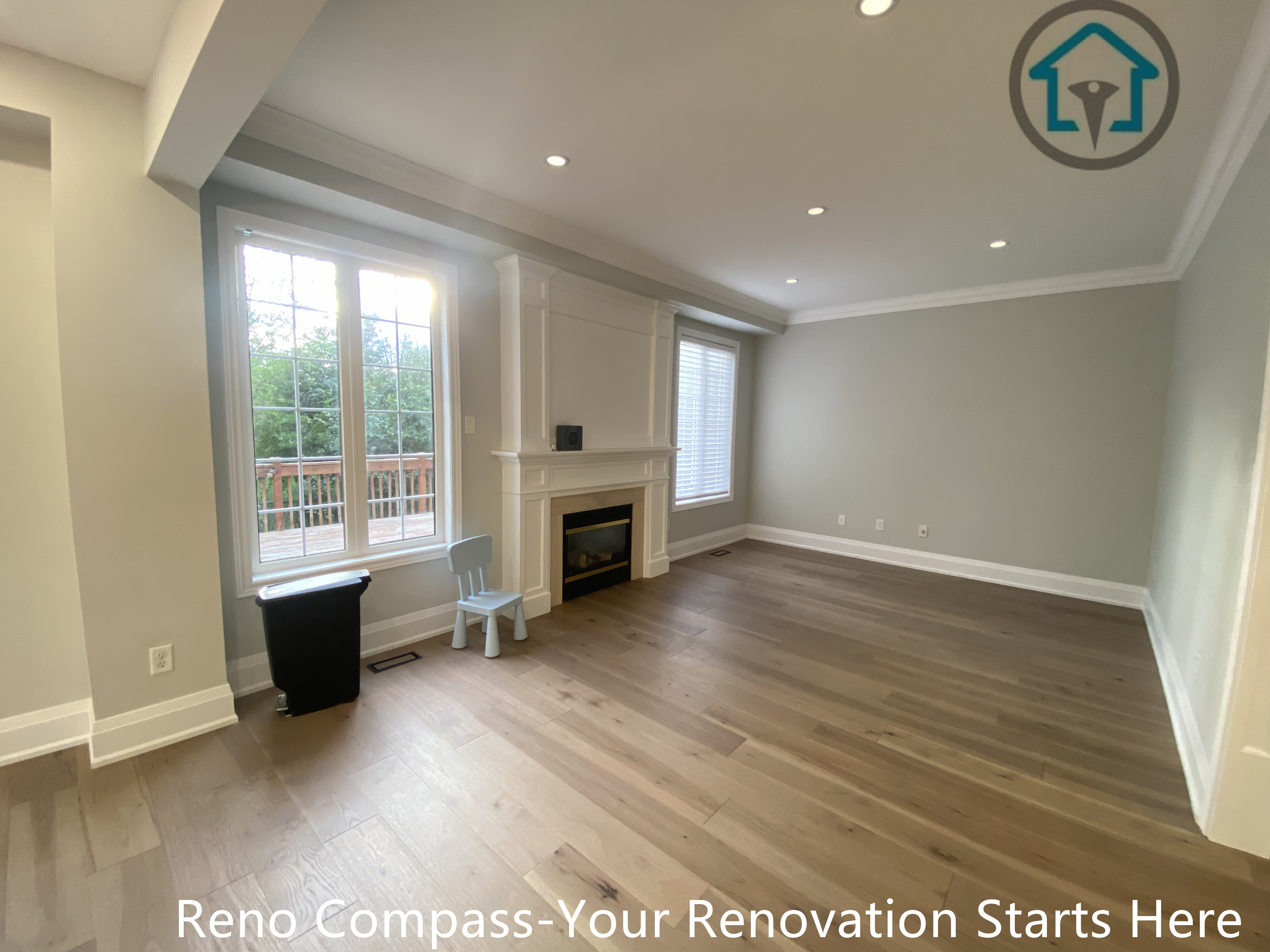 This image showcases a renovated living room completed as part of a flooring renovation project in Richmond Hill. The space features wide-plank hardwood flooring, a classic fireplace surround, recessed ceiling lighting, and large windows that bring in abundant natural light. Clean wall finishes and well-defined proportions create a comfortable and balanced living area. Completed by a professional Toronto renovation company, this renovation focuses on long-lasting materials, functional layout, and a timeless interior design suited for everyday family living.
