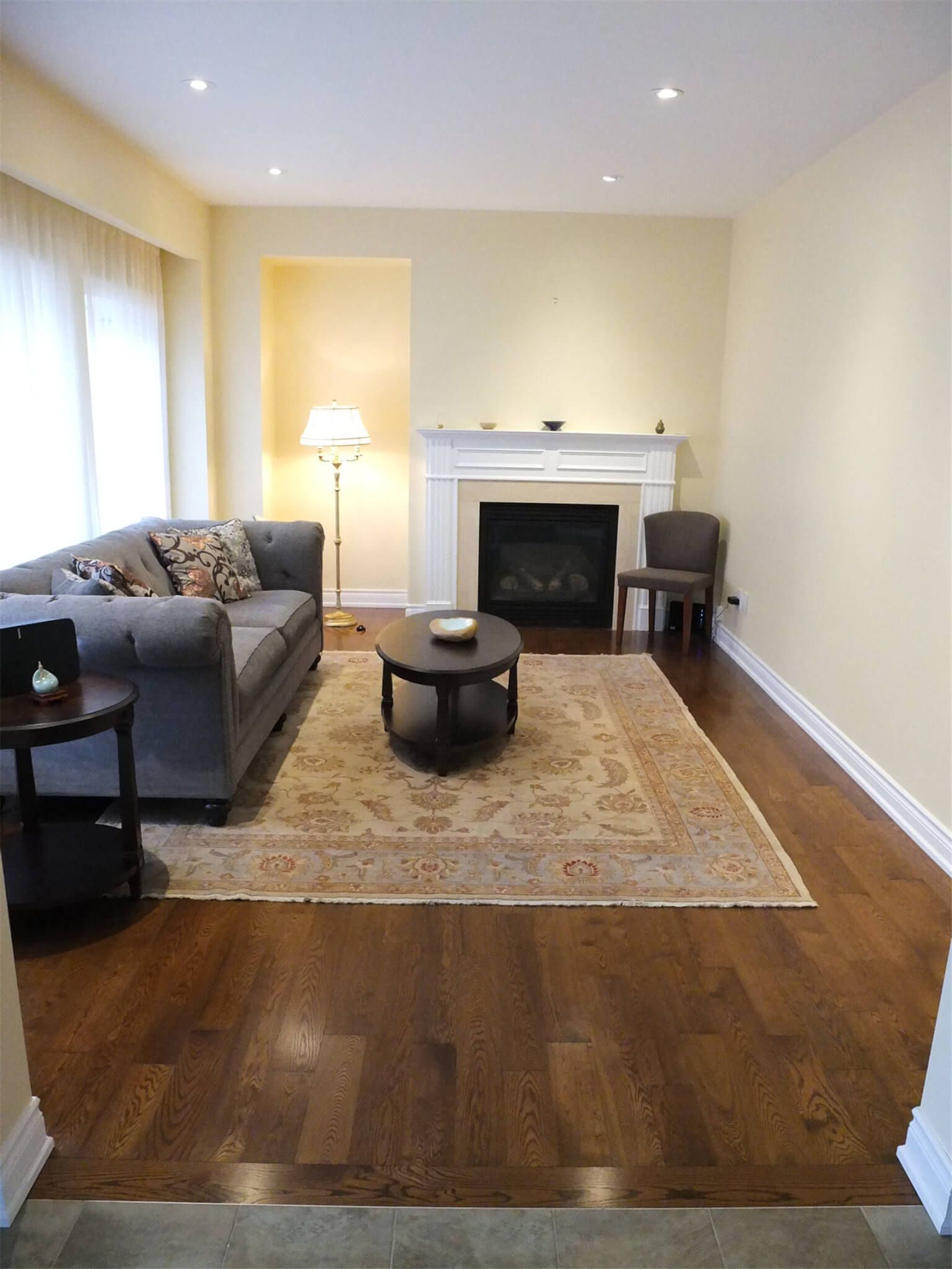 This Aurora flooring renovation showcases newly installed hardwood flooring in a cozy living room space featuring a classic fireplace and elegant seating area. The rich wood flooring enhances the warmth of the room and pairs beautifully with the neutral wall tones and traditional décor. Completed by a trusted Toronto renovation company, the flooring upgrade improves both the visual appeal and long-term durability of this comfortable living area.