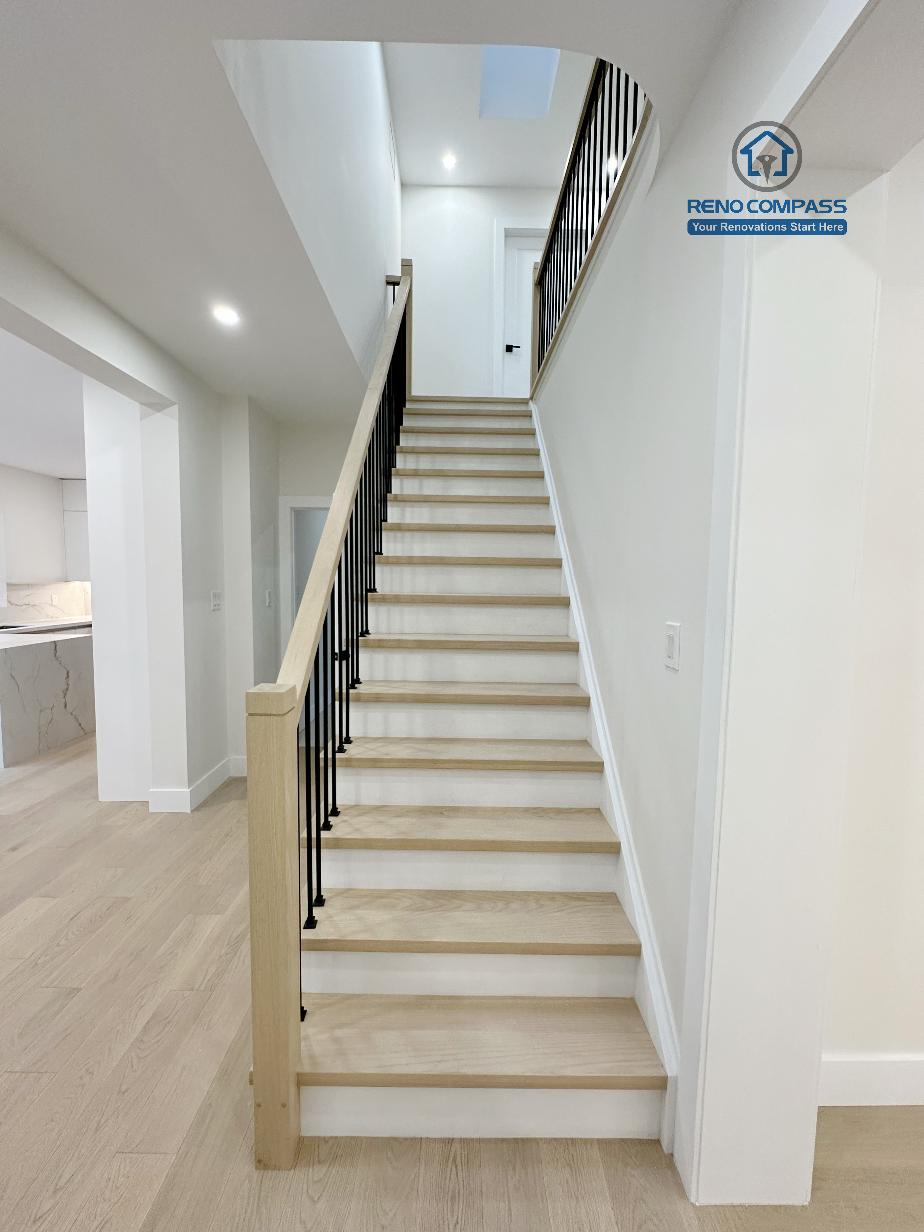 Modern staircase renovation in a Richmond Hill home featuring light wood stair treads, white risers, and sleek black metal railings, creating a clean, safe, and contemporary transition between floors.