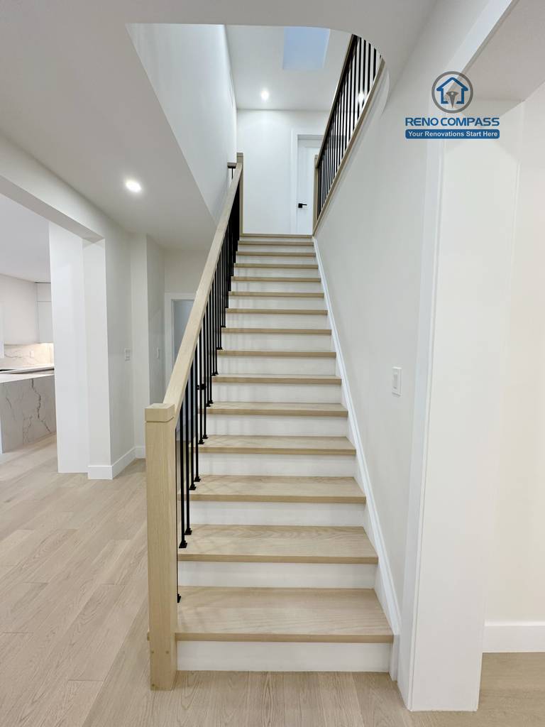 Modern staircase renovation in a Richmond Hill home featuring light wood stair treads, white risers, and sleek black metal railings, creating a clean, safe, and contemporary transition between floors.
