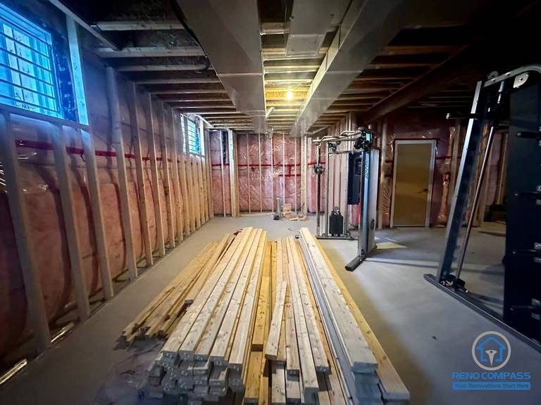 Unfinished basement before renovation in Newmarket showing exposed framing, insulation, and open space. Preparation stage before full basement transformation.
