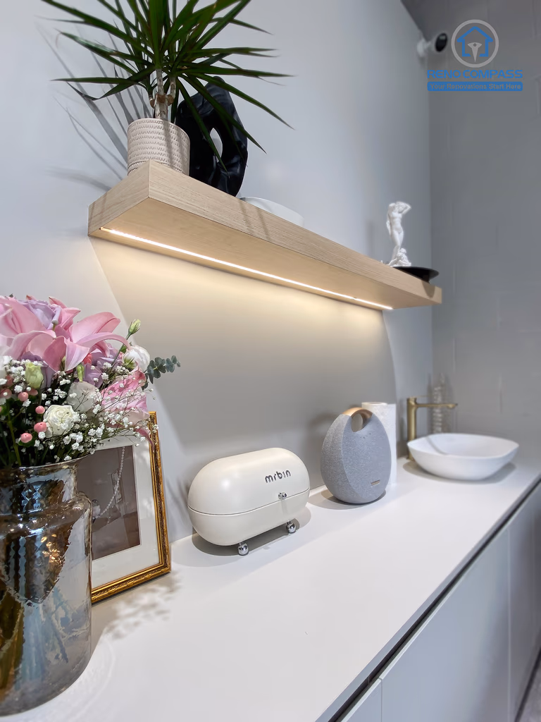 This image features a custom cabinetry and utility counter designed as part of a crystal shop renovation in Markham. The space includes built-in storage cabinets, a minimalist countertop with integrated sink, floating display shelf, and carefully styled decorative elements. Soft neutral finishes and functional layout support daily retail operations while maintaining a calm, curated aesthetic. As a Toronto renovation company, Reno Compass delivers retail renovation solutions that combine practical workspace design with refined visual presentation.