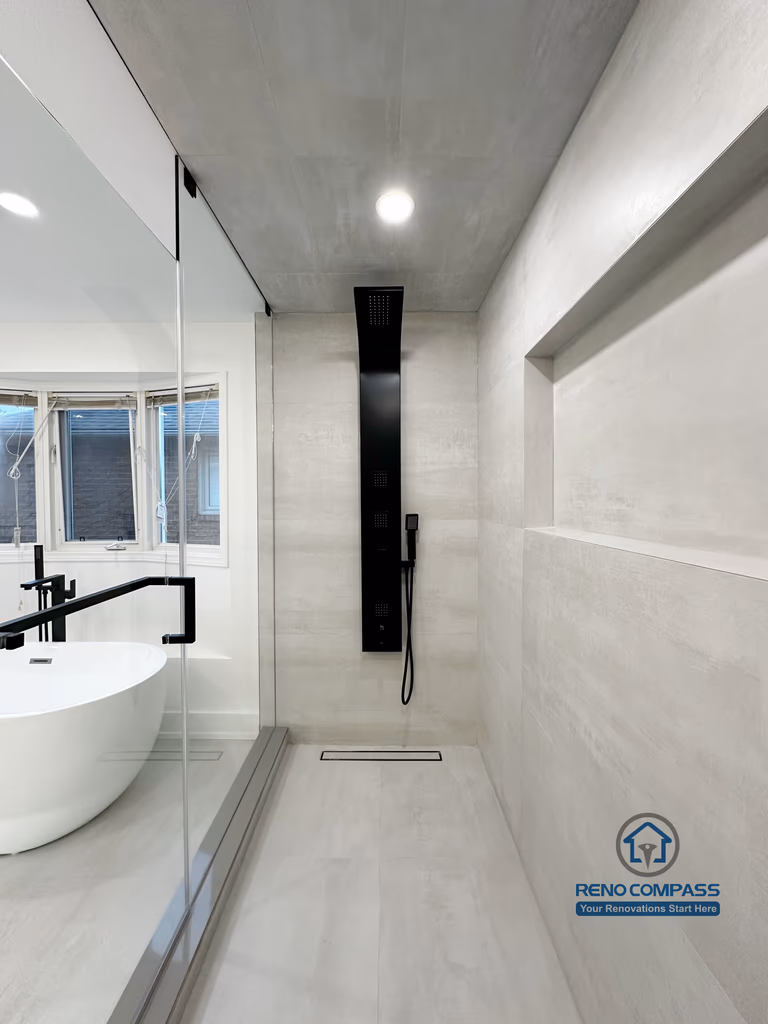 Oakville bathroom renovation showcasing a modern black shower panel, linear floor drain, large-format tile walls, and frameless glass enclosure, completed by a professional Toronto renovation company.