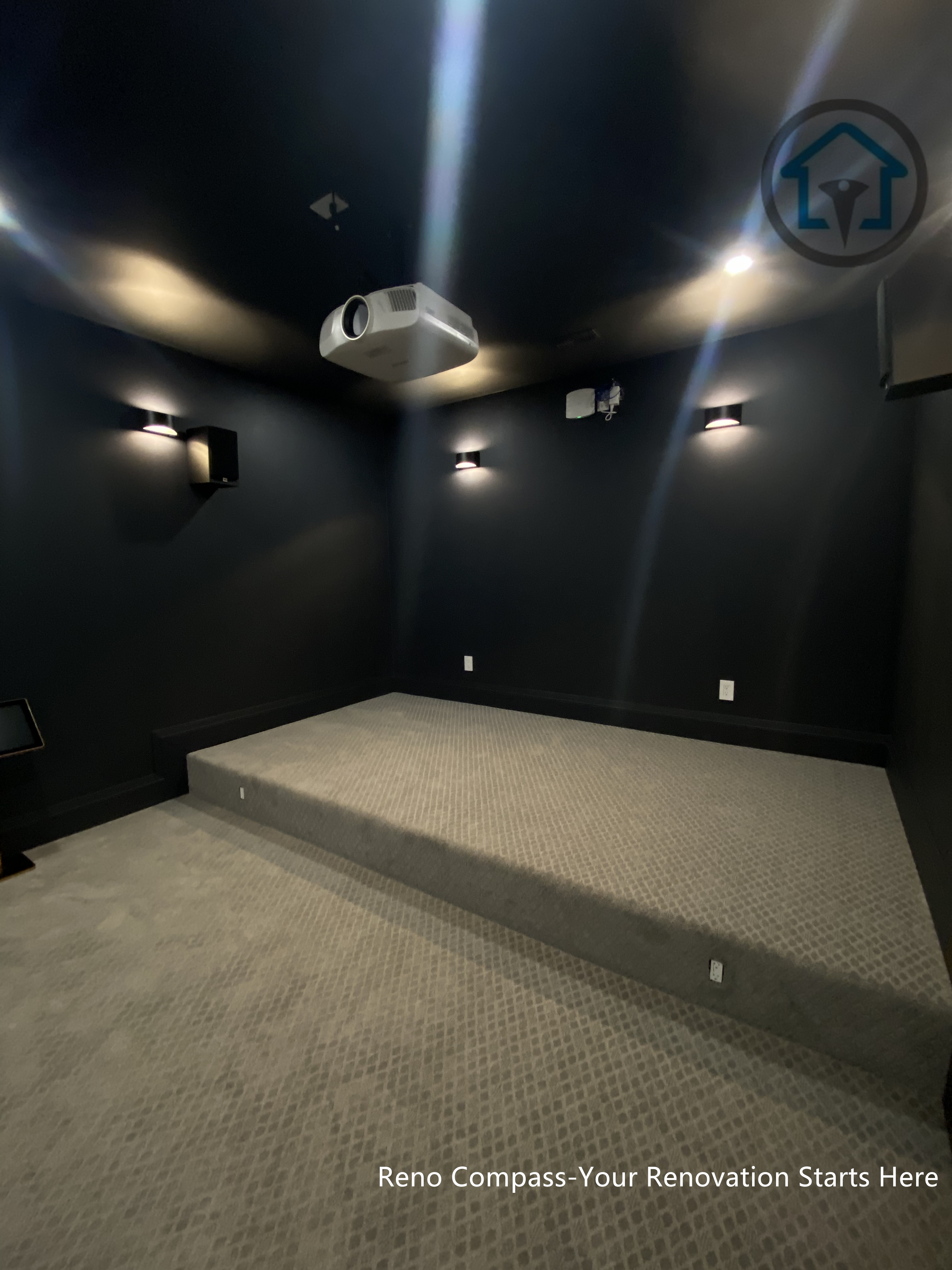 This image features a custom basement home theater renovation in Richmond Hill, designed with dark wall finishes, wall-mounted ambient lighting, and a raised platform for optimal viewing experience. The enclosed layout enhances sound control and visual focus, creating a private cinematic environment within the home. Completed by Reno Compass, this home theater renovation demonstrates thoughtful space planning and lighting design tailored for immersive entertainment in a modern basement setting.