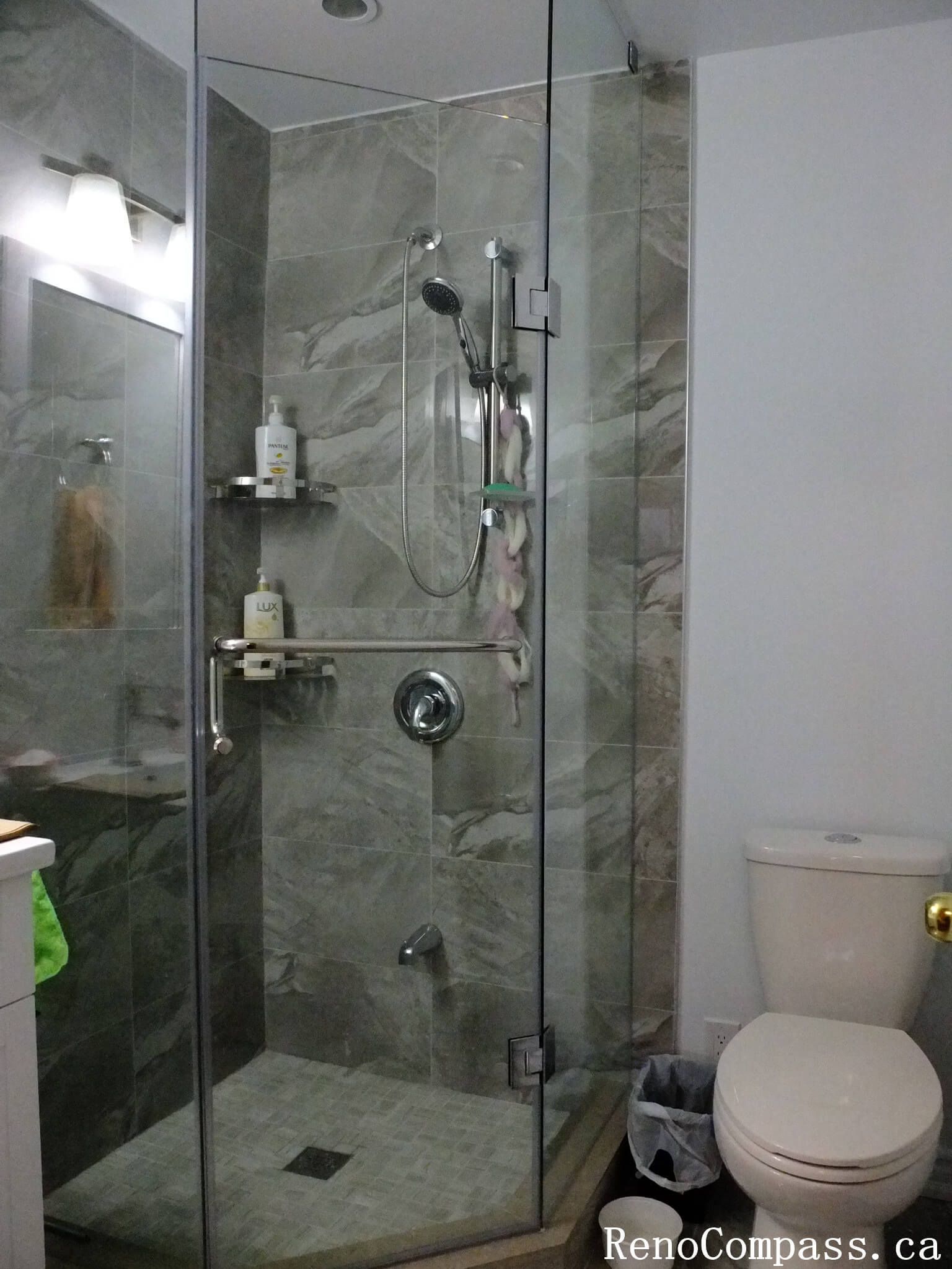 Bathroom renovation in North York featuring marble-look porcelain shower wall tiles, chrome shower fixtures, and built-in corner shelves for daily use. This Toronto interior renovation highlights clean detailing, practical storage integration, and durable finishes designed for long-term bathroom performance.