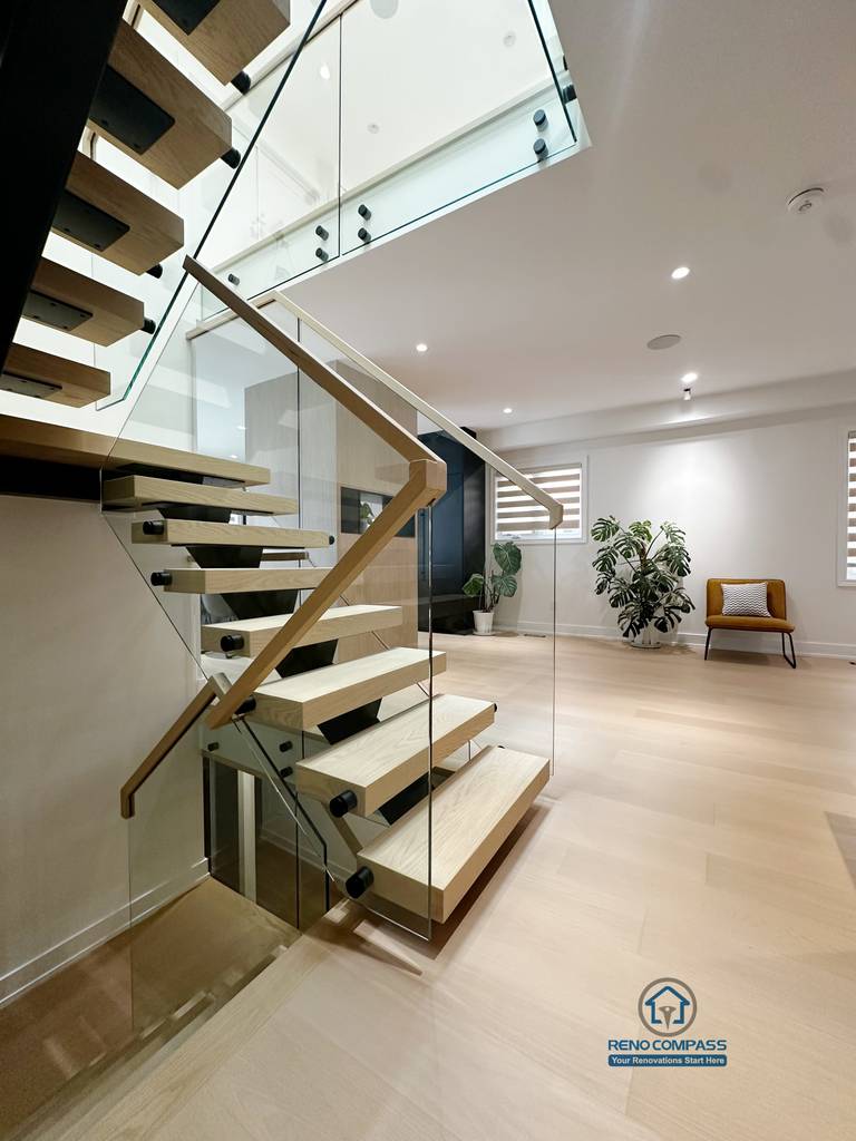 This detail view highlights the craftsmanship of the floating steel staircase, featuring solid wood treads paired with a tempered glass railing system. The design emphasizes clean lines, structural clarity, and safety, while maintaining visual openness and a seamless connection between levels.