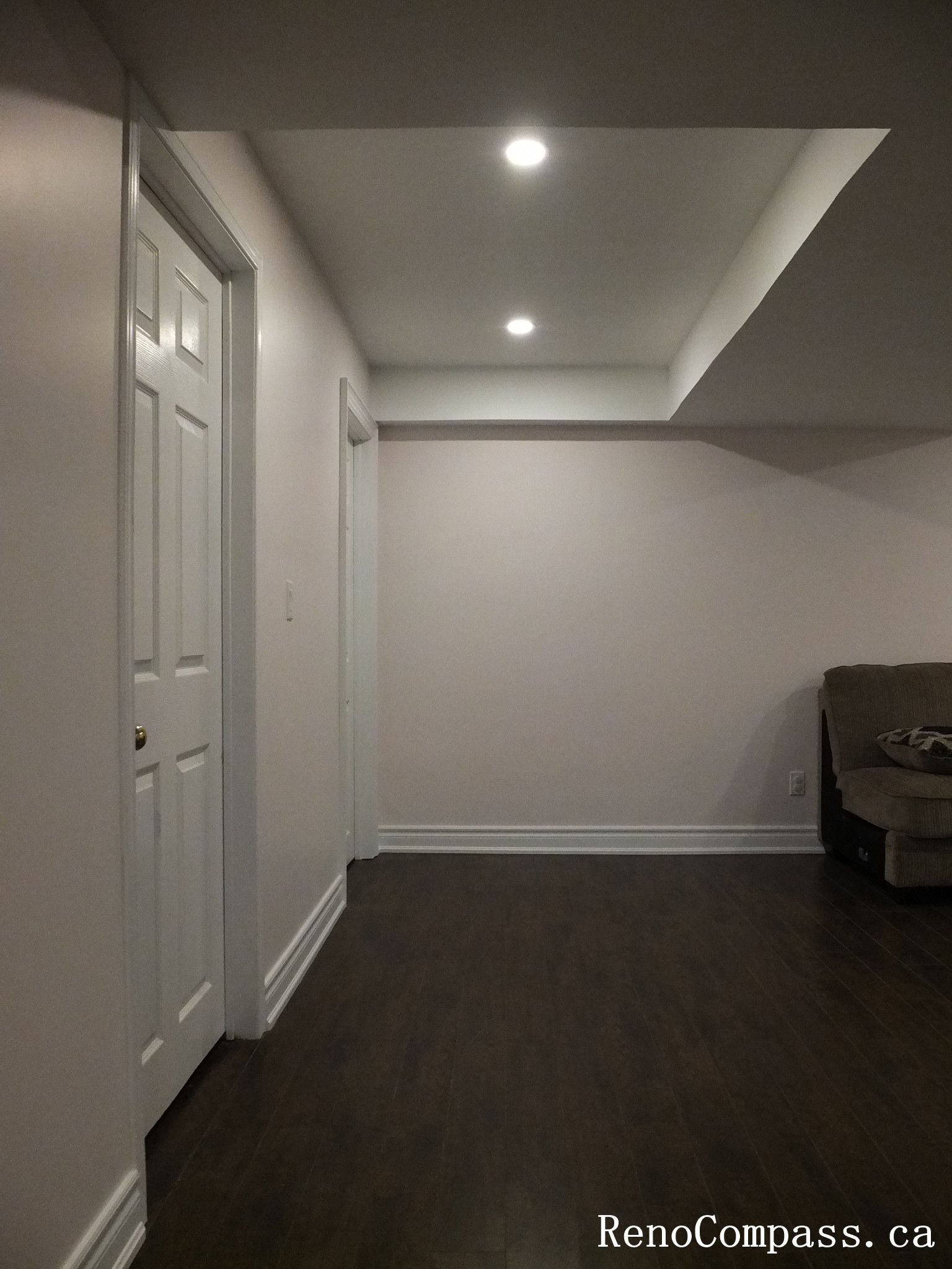 Finished basement hallway renovation in Newmarket showcasing clean white trim, modern recessed pot lighting, smooth drywall finishes, and dark hardwood flooring. This thoughtfully designed lower-level interior was completed by a professional Toronto Renovation Company to enhance flow and functionality between living areas.