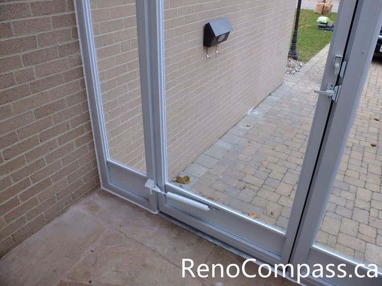 This image shows the door closer mechanism installed on a custom glass storm door at a North York home entrance. The hydraulic door closer ensures smooth and controlled closing, preventing the door from slamming while improving durability and daily usability. Combined with the aluminum frame and full glass panels, the storm door enclosure provides added insulation and protection from wind, rain, and snow. Installed by an experienced Toronto renovation team, this entrance upgrade enhances both practicality and long-term performance for the homeowner.