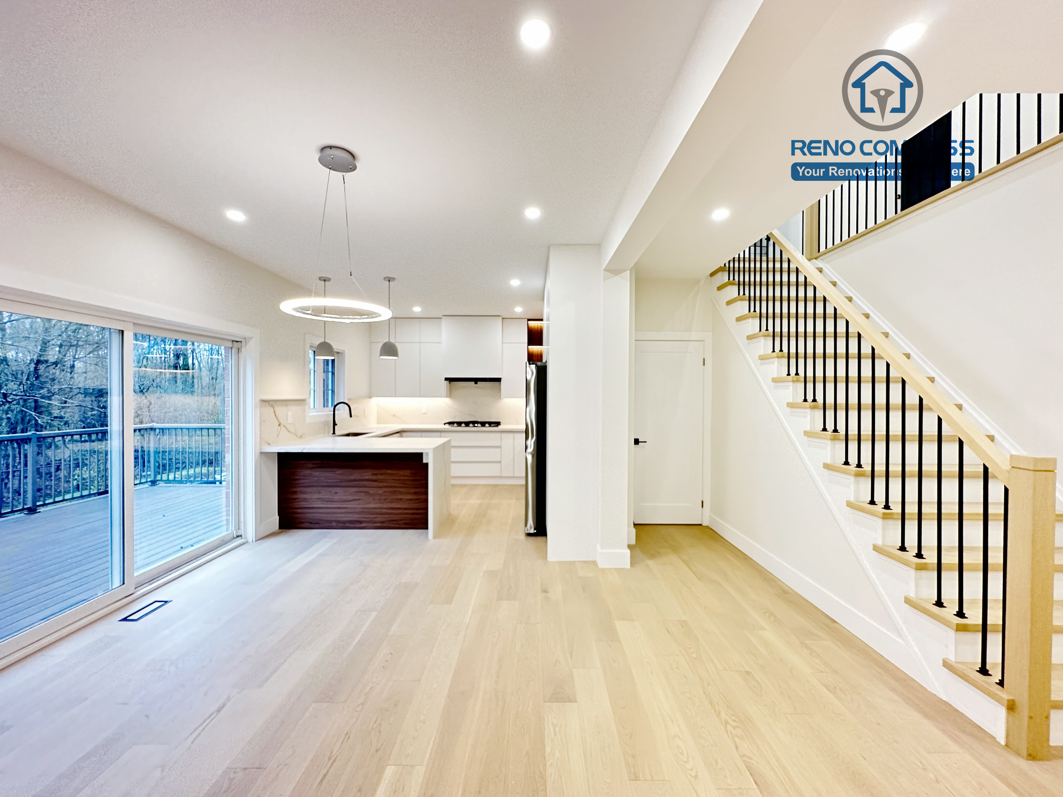 Open-concept kitchen and stair renovation in a Richmond Hill home featuring light-tone hardwood flooring, a modern staircase with wood treads and black railings, and a seamless flow between kitchen and living spaces.