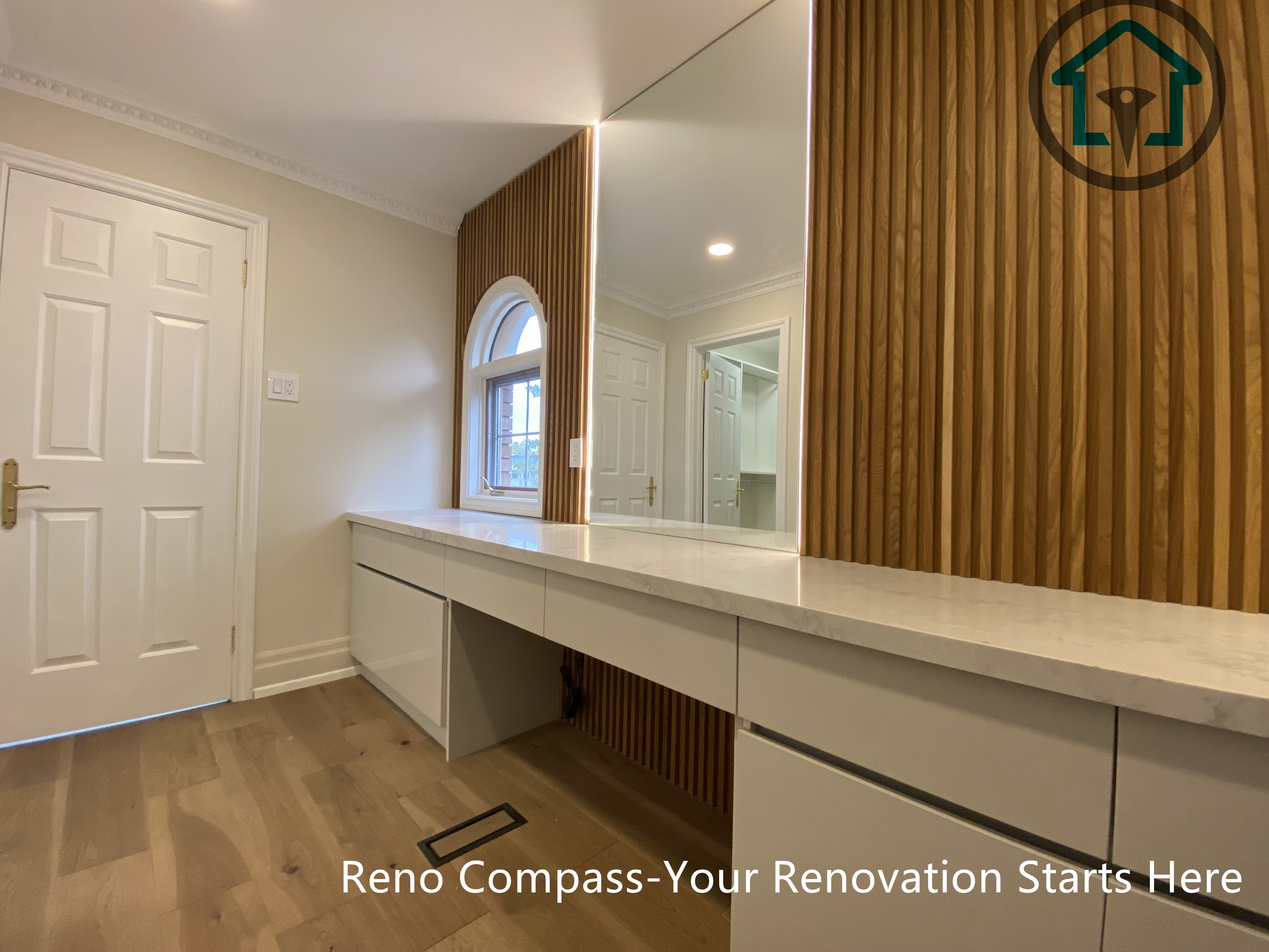 This custom bathroom vanity features clean-lined cabinetry, integrated LED mirror lighting, and warm wood panel accents, creating a balanced blend of functionality and modern design.