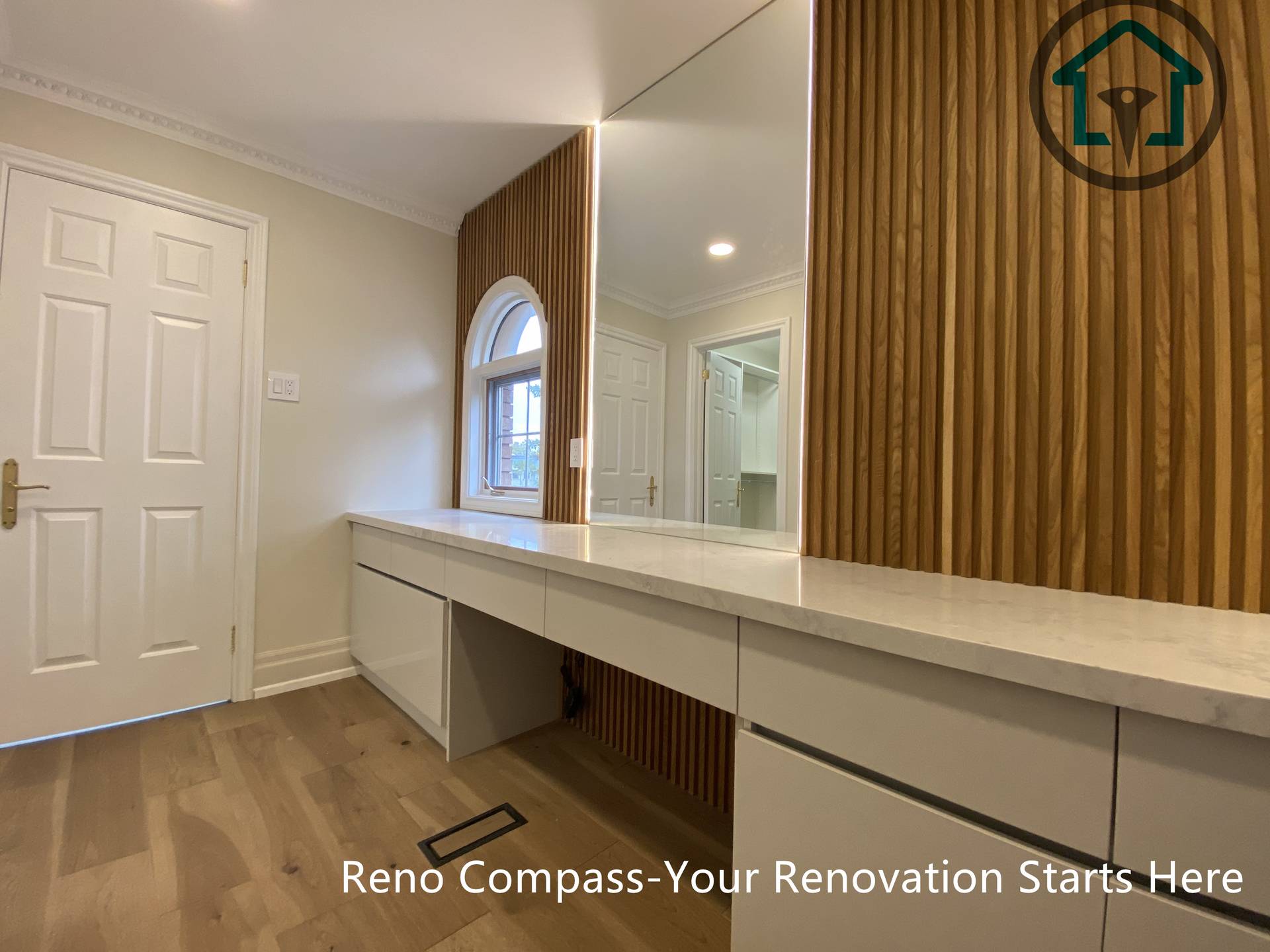 This custom bathroom vanity features clean-lined cabinetry, integrated LED mirror lighting, and warm wood panel accents, creating a balanced blend of functionality and modern design.