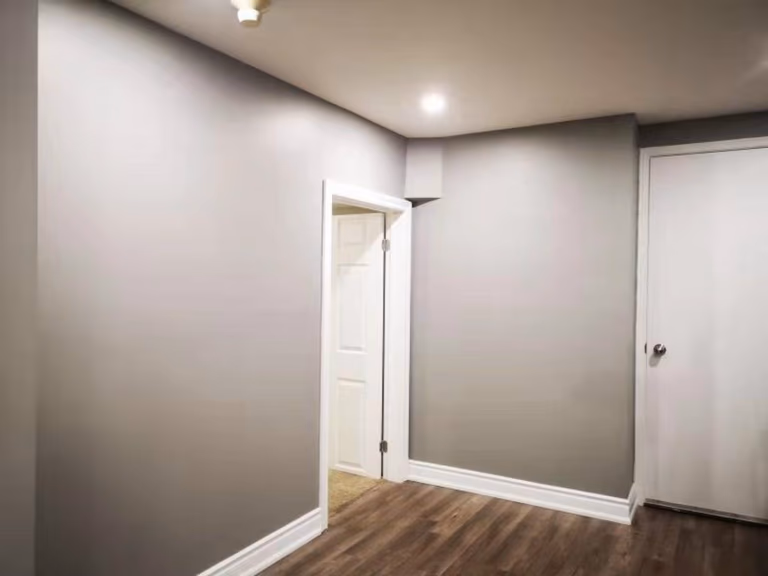 This completed Mississauga basement renovation features smooth painted walls, upgraded trim, modern vinyl flooring, and clean interior door finishes. The bright and functional layout highlights the attention to detail provided by a professional Toronto renovation company, creating a comfortable and versatile living space.