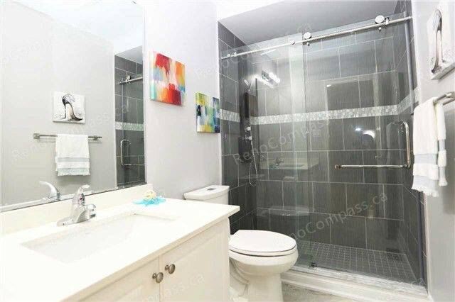 A modern bathroom remodel featuring a frameless glass shower, elegant grey tiles, and a crisp white vanity. This sleek Toronto renovation blends functionality with sophisticated design.