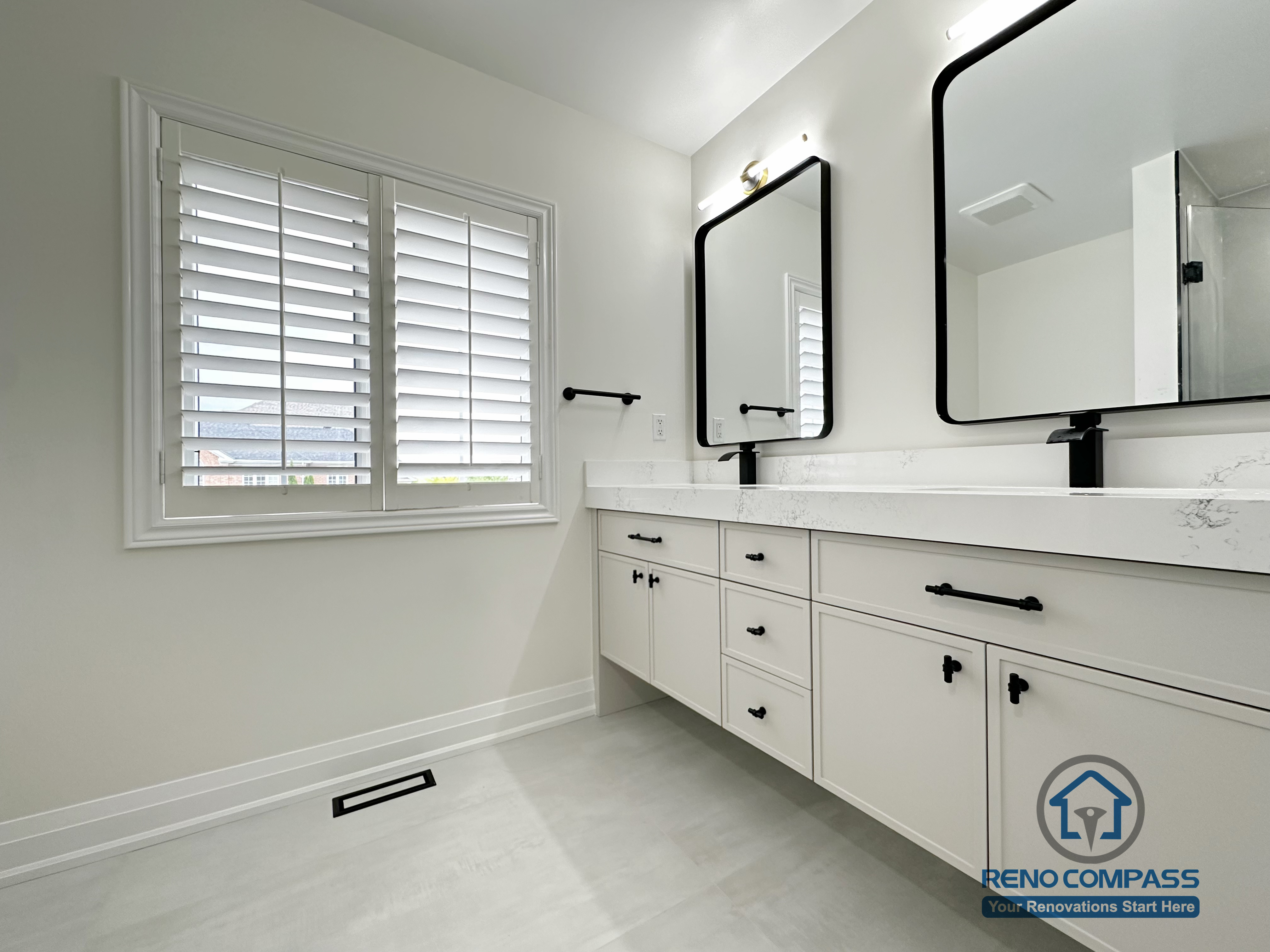 This Markham bathroom renovation features a spacious double vanity with quartz countertops, matte black fixtures, and oversized mirrors. Natural light from the large window enhances the clean layout, creating a bright and comfortable bathroom designed for daily use and long-term durability.