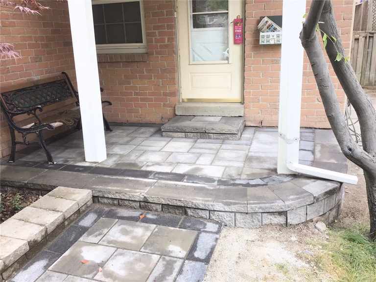 This Oakville interlocking project features a beautifully designed front entrance patio with curved stone steps, modern grey pavers, and a seamless transition from walkway to porch. The layout enhances both curb appeal and functionality, providing a clean, durable outdoor space that complements the home’s brick exterior. Ideal for homeowners looking to upgrade their entrance with elegant and long-lasting interlocking stonework.