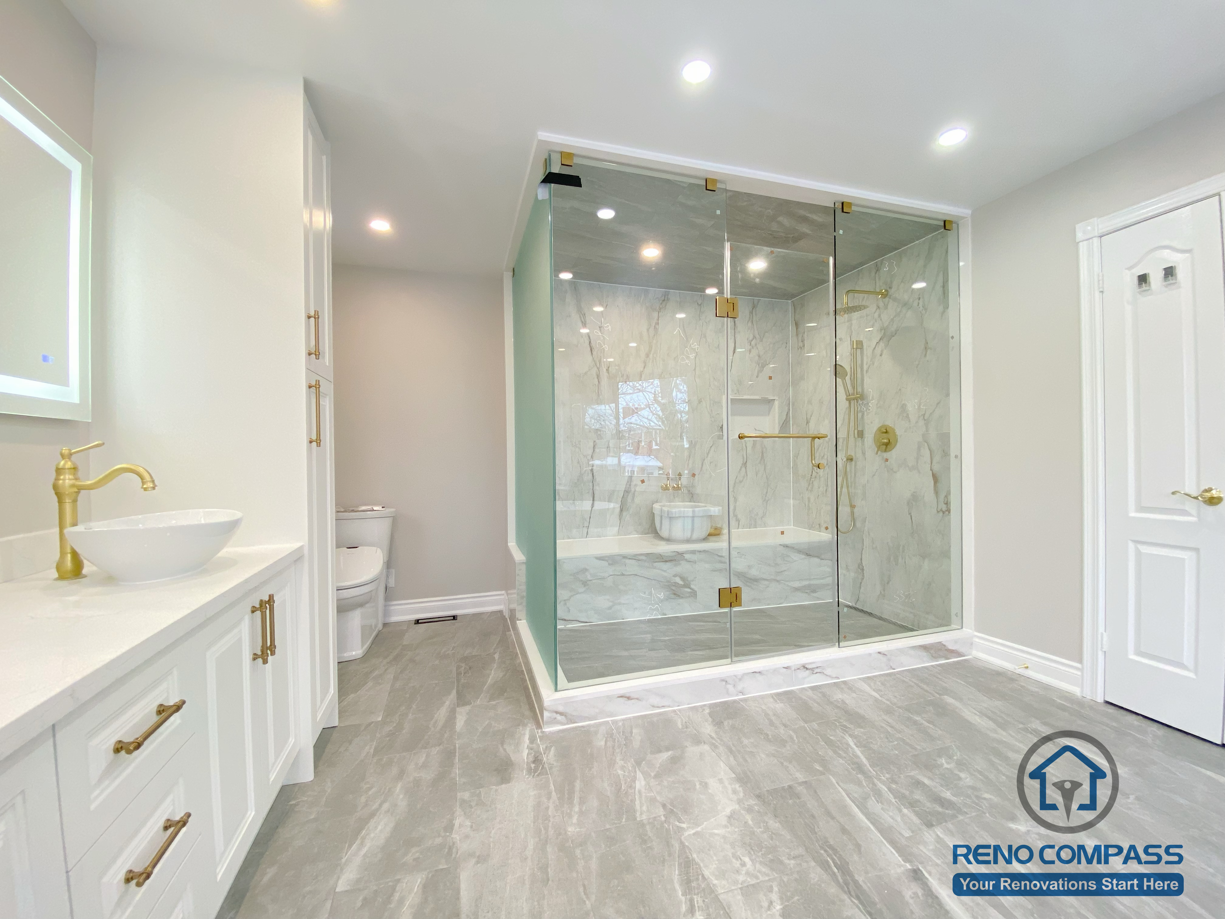 This Richmond Hill bathroom renovation showcases a bright and elegant design featuring a frameless glass shower enclosure, built-in bathtub, marble-style wall tiles, and gold-finish fixtures.