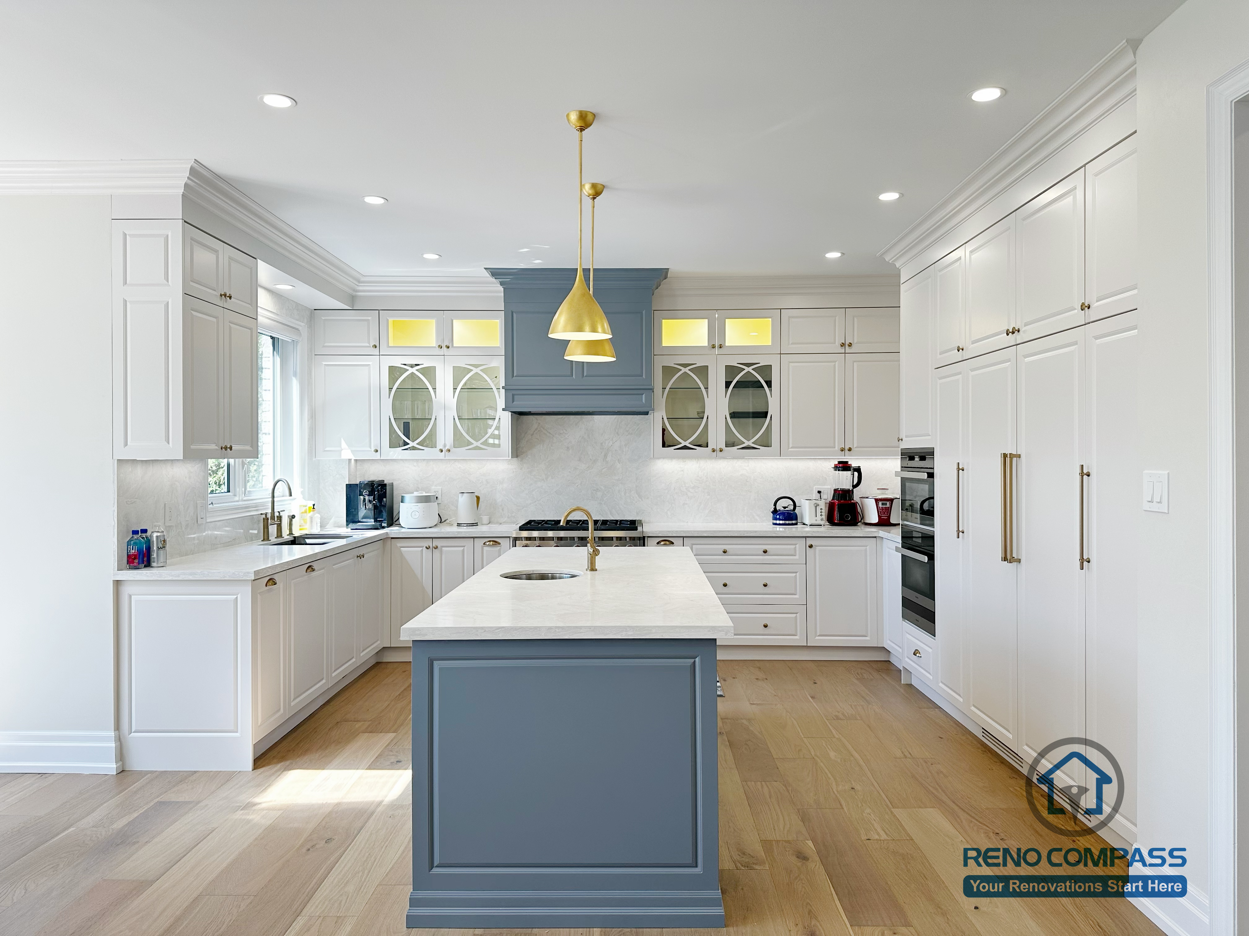 This North York kitchen renovation features a spacious central island with quartz countertops, custom cabinetry in a soft blue and white palette, and integrated pendant lighting. The open-concept layout enhances natural light and flow between the kitchen and dining area, creating a functional and elegant space designed for everyday living and entertaining. Completed by Reno Compass with a focus on craftsmanship, proportion, and long-term usability.