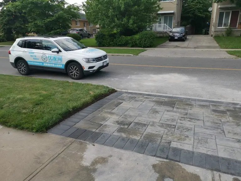 Interlocking driveway and walkway completed as part of a North York exterior renovation project. This installation features durable concrete pavers arranged in a clean, modern pattern, creating a seamless transition between the driveway, sidewalk, and front yard landscaping. The curved edge detailing improves visual flow while maintaining proper alignment and surface stability. Designed for long-term performance and curb appeal, this driveway interlocking project was completed by a Toronto renovation company with a focus on craftsmanship, drainage consideration, and everyday functionality.
