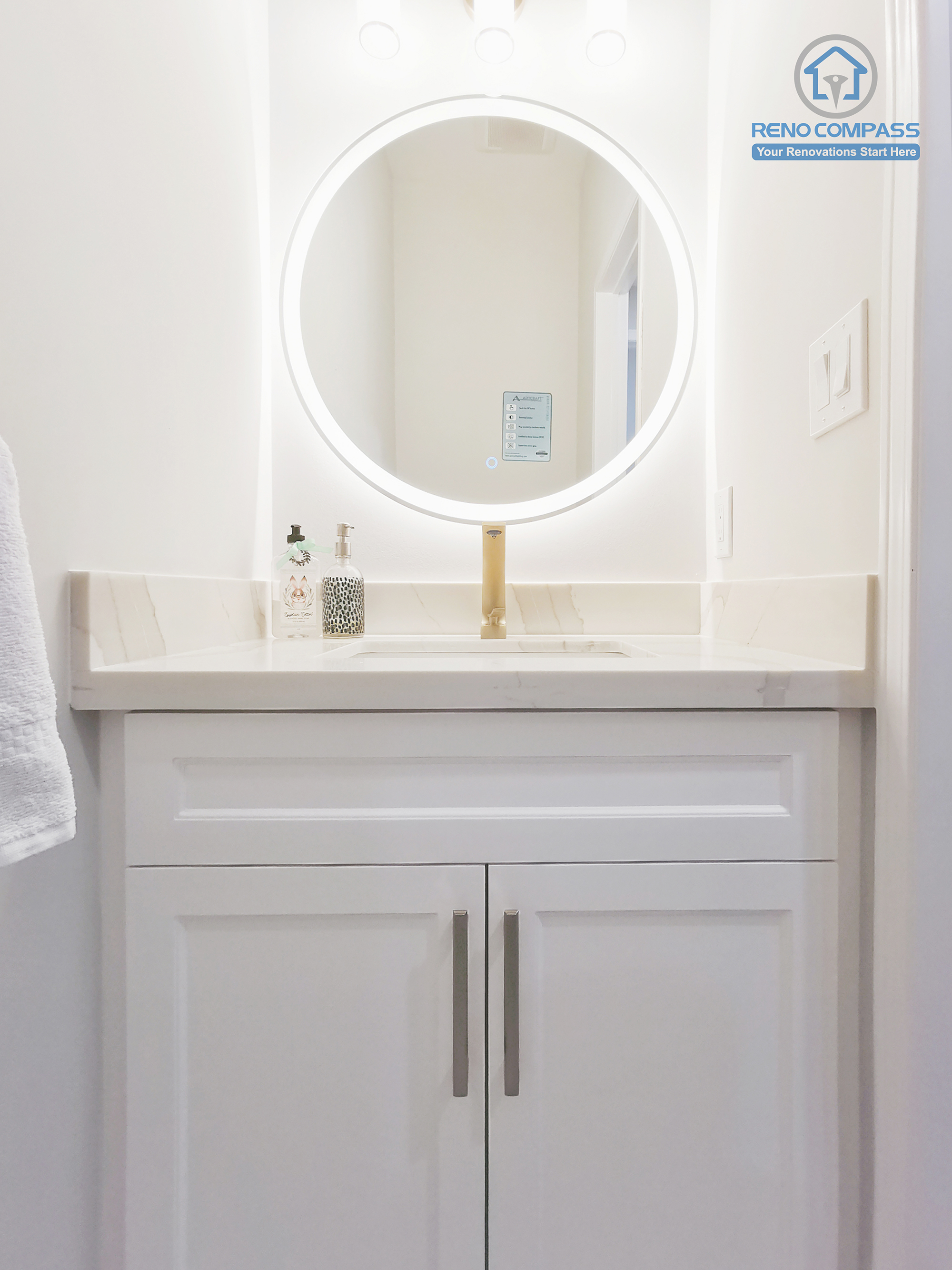 This Markham interior renovation features a refined bathroom vanity designed with a clean, understated aesthetic and practical daily use in mind. The custom white shaker vanity provides concealed storage while maintaining a balanced, symmetrical appearance. A quartz countertop offers durability and easy maintenance, paired with a warm-toned faucet that adds subtle contrast. The circular LED mirror introduces soft, even illumination, enhancing visibility without harsh glare and contributing to a calm, spa-like atmosphere. Completed by Reno Compass, this bathroom renovation reflects careful material coordination, proportion control, and a timeless design approach tailored for modern Markham homes.