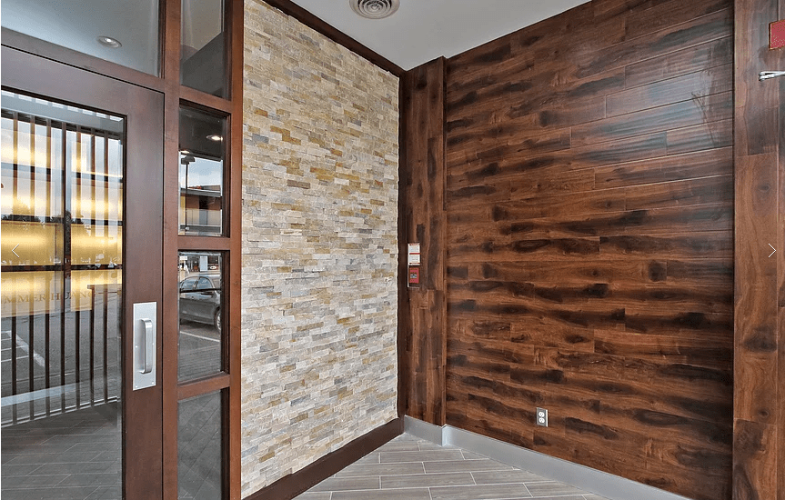 This Markham restaurant renovation by Reno Compass Inc. highlights a stylish feature wall combining natural stacked stone and rich wood panel finishes. The entrance area is designed to create a warm, welcoming first impression while maintaining durability for high-traffic commercial use. With premium materials, clean tile flooring, and detailed craftsmanship, this restaurant interior showcases a modern yet cozy atmosphere tailored for upscale dining experiences.