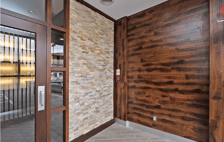 This Markham restaurant renovation by Reno Compass Inc. highlights a stylish feature wall combining natural stacked stone and rich wood panel finishes. The entrance area is designed to create a warm, welcoming first impression while maintaining durability for high-traffic commercial use. With premium materials, clean tile flooring, and detailed craftsmanship, this restaurant interior showcases a modern yet cozy atmosphere tailored for upscale dining experiences.