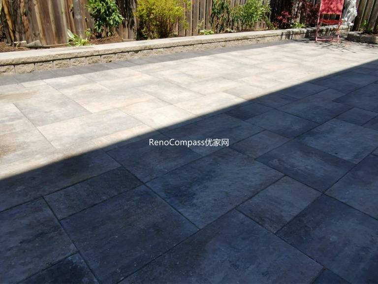 Modern Mississauga backyard patio featuring interlocking stone flooring, raised retaining wall, and landscaped garden beds, creating a functional and elegant outdoor living space.