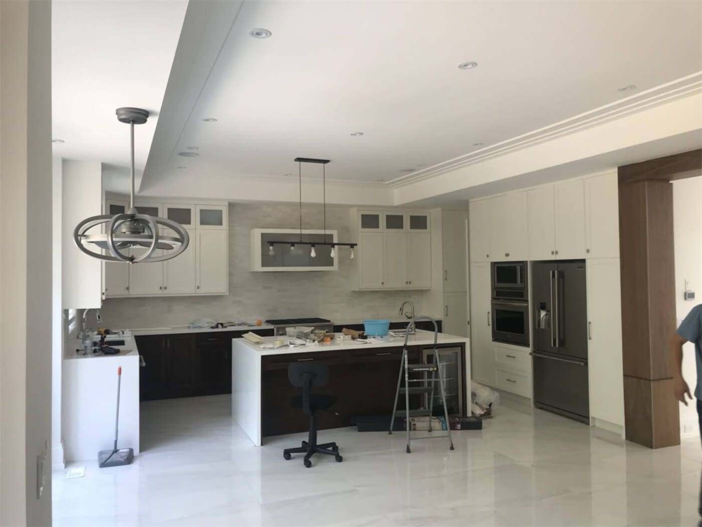 This image features a modern open-concept kitchen painting and interior finishing project in Toronto. The space includes freshly painted ceilings and walls, custom cabinetry, a large central island, and premium lighting fixtures that create a bright and elegant atmosphere. Professional preparation and precision painting ensure smooth surfaces and clean lines throughout the kitchen and living area. Completed by a trusted Toronto renovation and painting team, this project highlights high-end craftsmanship, contemporary design, and durable finishes that enhance both functionality and property value.