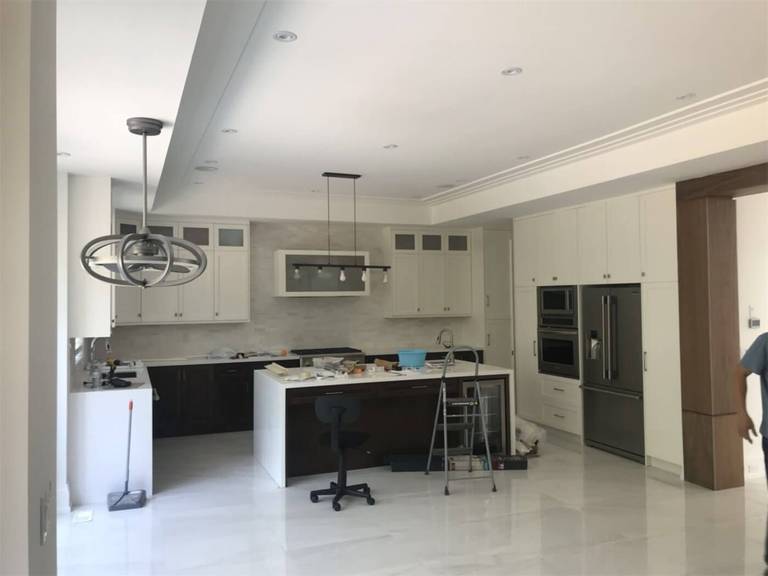 This image features a modern open-concept kitchen painting and interior finishing project in Toronto. The space includes freshly painted ceilings and walls, custom cabinetry, a large central island, and premium lighting fixtures that create a bright and elegant atmosphere. Professional preparation and precision painting ensure smooth surfaces and clean lines throughout the kitchen and living area. Completed by a trusted Toronto renovation and painting team, this project highlights high-end craftsmanship, contemporary design, and durable finishes that enhance both functionality and property value.