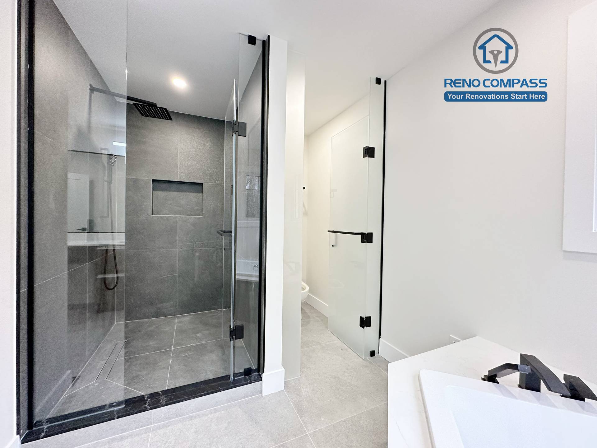 Modern bathroom renovation in Richmond Hill featuring a black-framed glass shower enclosure, large-format grey tile walls and flooring, and a clean, minimalist design that enhances both functionality and visual space.