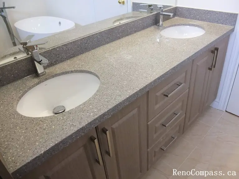 Bathroom renovation in North York highlighting a quartz countertop double sink vanity with integrated storage, modern chrome faucets, and clean-lined cabinetry. This Toronto interior renovation emphasizes durability, ease of maintenance, and practical design for shared bathroom spaces.
