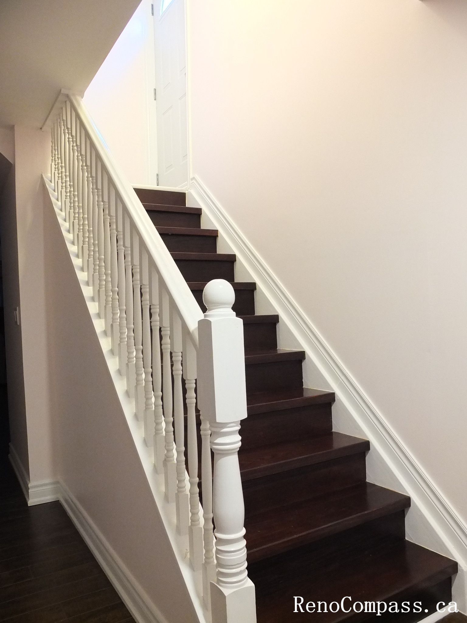This Newmarket interior renovation features a beautifully finished staircase connecting the basement and upper level. The staircase includes rich dark wood steps paired with classic white spindles and railing, creating a clean contrast that enhances the overall interior design. Smooth wall finishes and matching trim details give the space a bright and polished look while maintaining durability for everyday use. Completed by Reno Compass Inc., this staircase renovation highlights quality craftsmanship and thoughtful design within a modern basement finishing project.