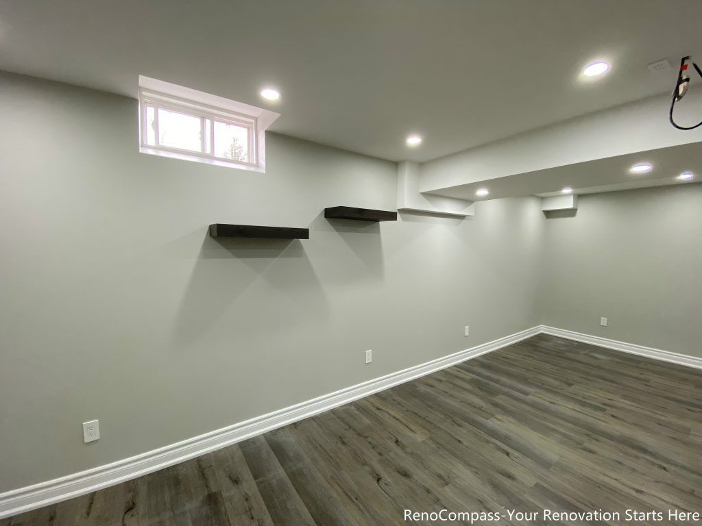 This Oakville basement renovation features a bright and modern finished space with upgraded flooring, smooth ceilings, recessed pot lights, and custom floating shelves for added functionality. The redesigned basement offers a clean and versatile layout ideal for a recreation room, home office, or family living area. Completed by a professional Toronto renovation company, this basement upgrade enhances lighting, storage, and overall comfort while increasing usable living space and long-term property value.